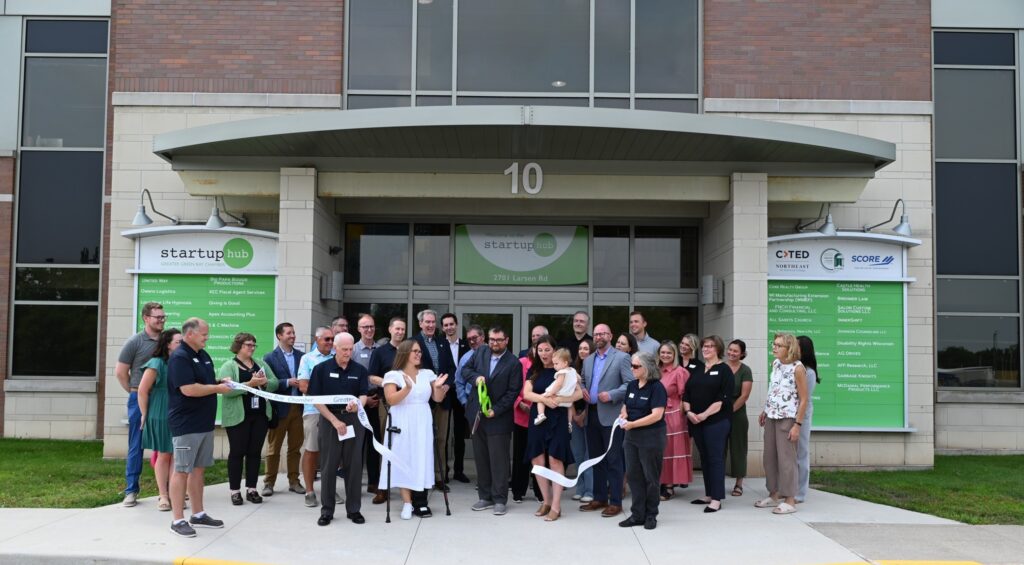 John Laughrin, founder of Four Leaf Communications, cuts the ribbon with his wife Kelly and daughter Clover alongside community members, elected officials, and Greater Green Bay Chamber representatives at the Startup Hub on August 12, 2025.