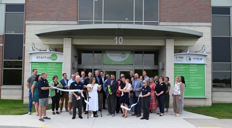 John Laughrin, founder of Four Leaf Communications, cuts the ribbon with his wife Kelly and daughter Clover alongside community members, elected officials, and Greater Green Bay Chamber representatives at the Startup Hub on August 12, 2025.