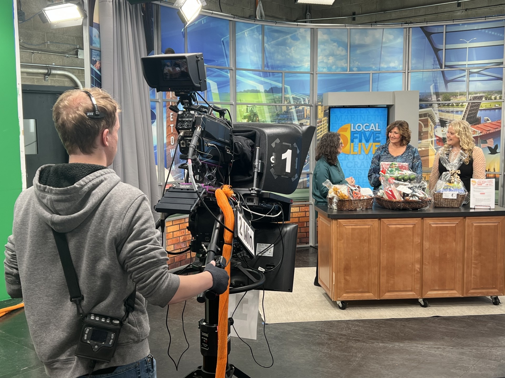 Behind-the-scenes view of a Local 5 Live TV interview at WFRV in Green Bay featuring Four Leaf Communications client Paula Jolly discussing Amanda’s House nonprofit fundraiser, with camera operator filming in studio.